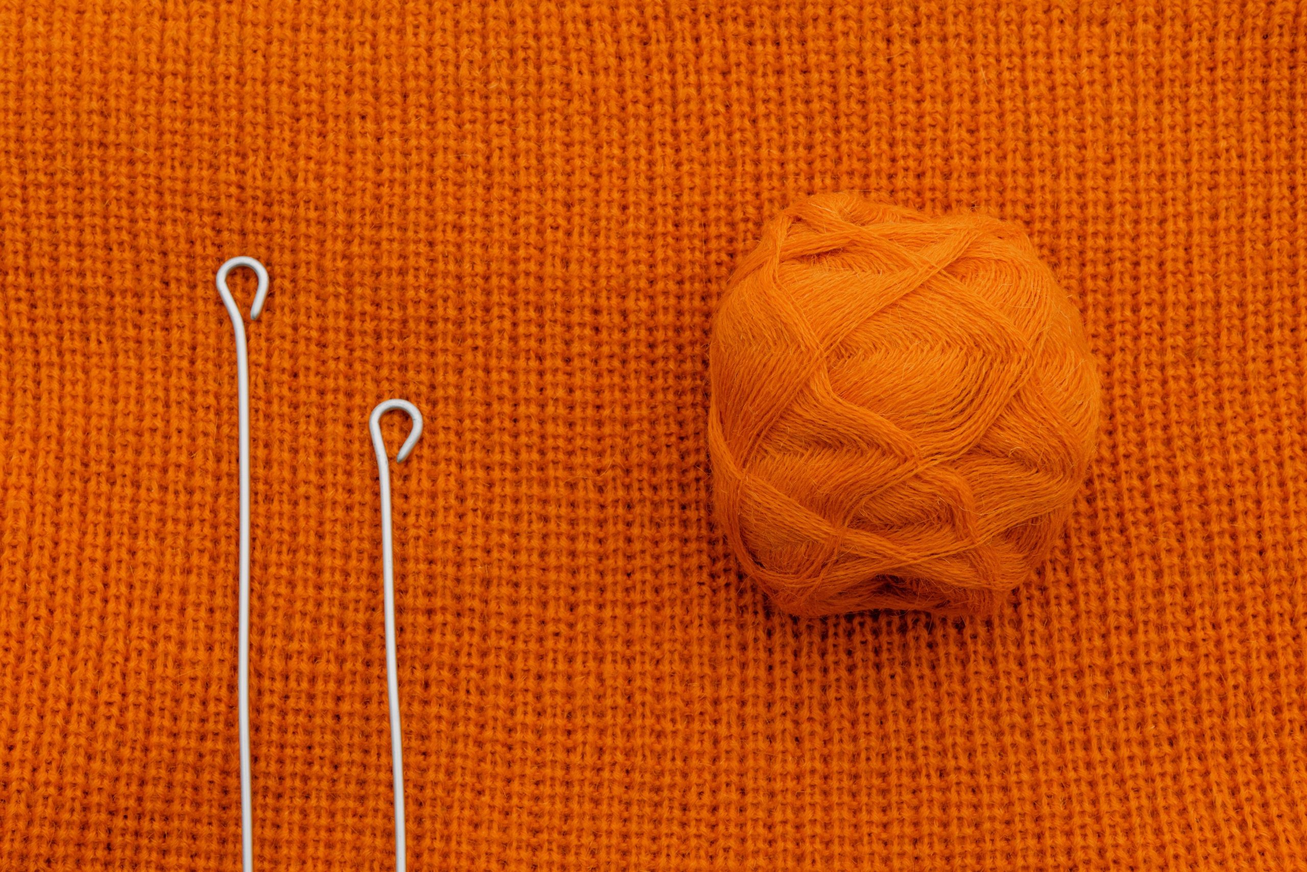 Pelote orange sur tricot avec aiguilles metal