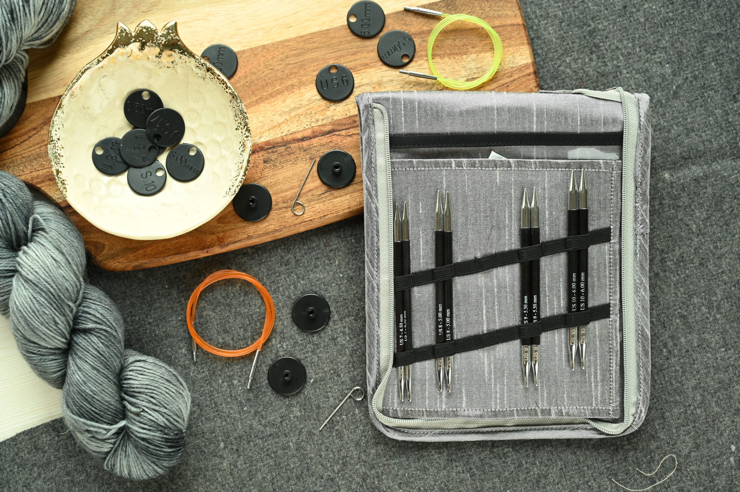 Outils tricot et accessoires arrangés sur tissu gris