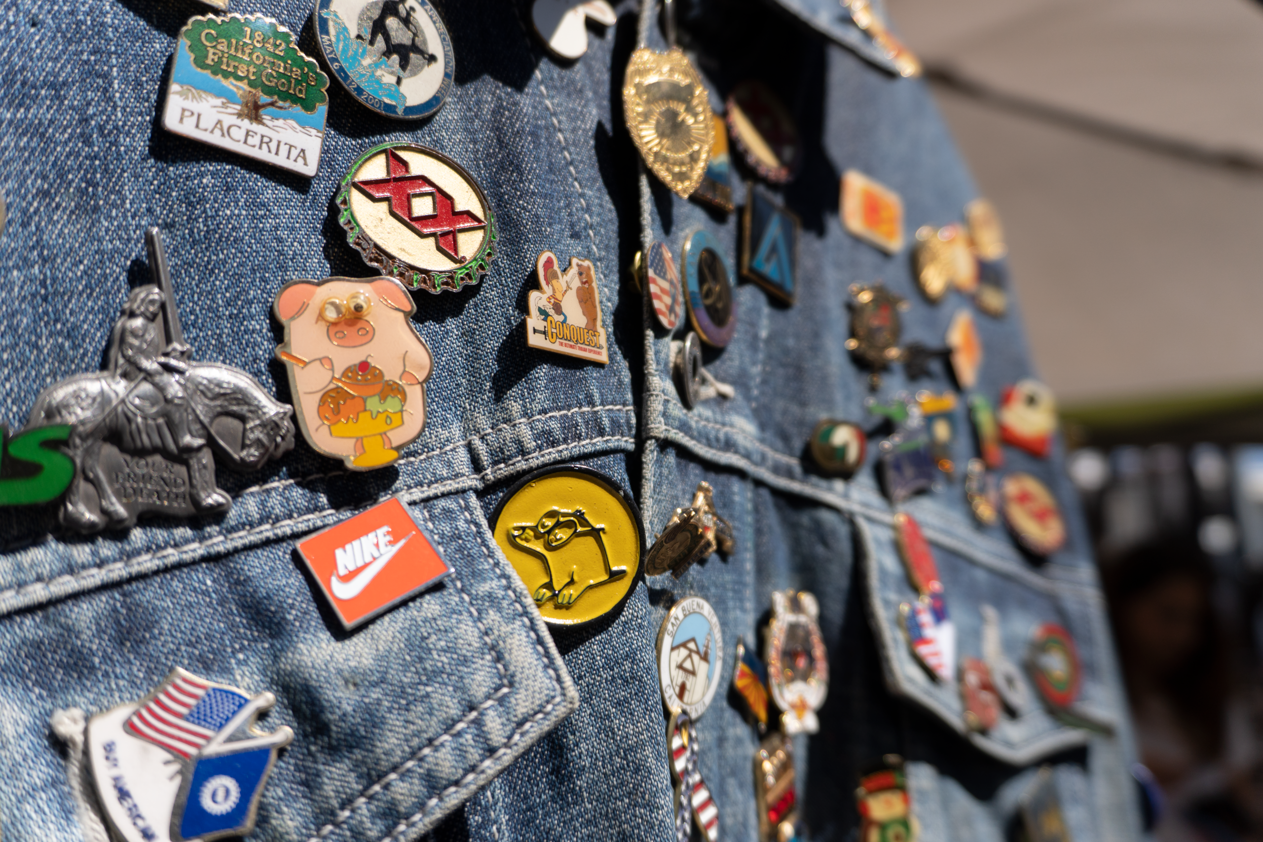Pins vibrants sur veste en denim au marché.