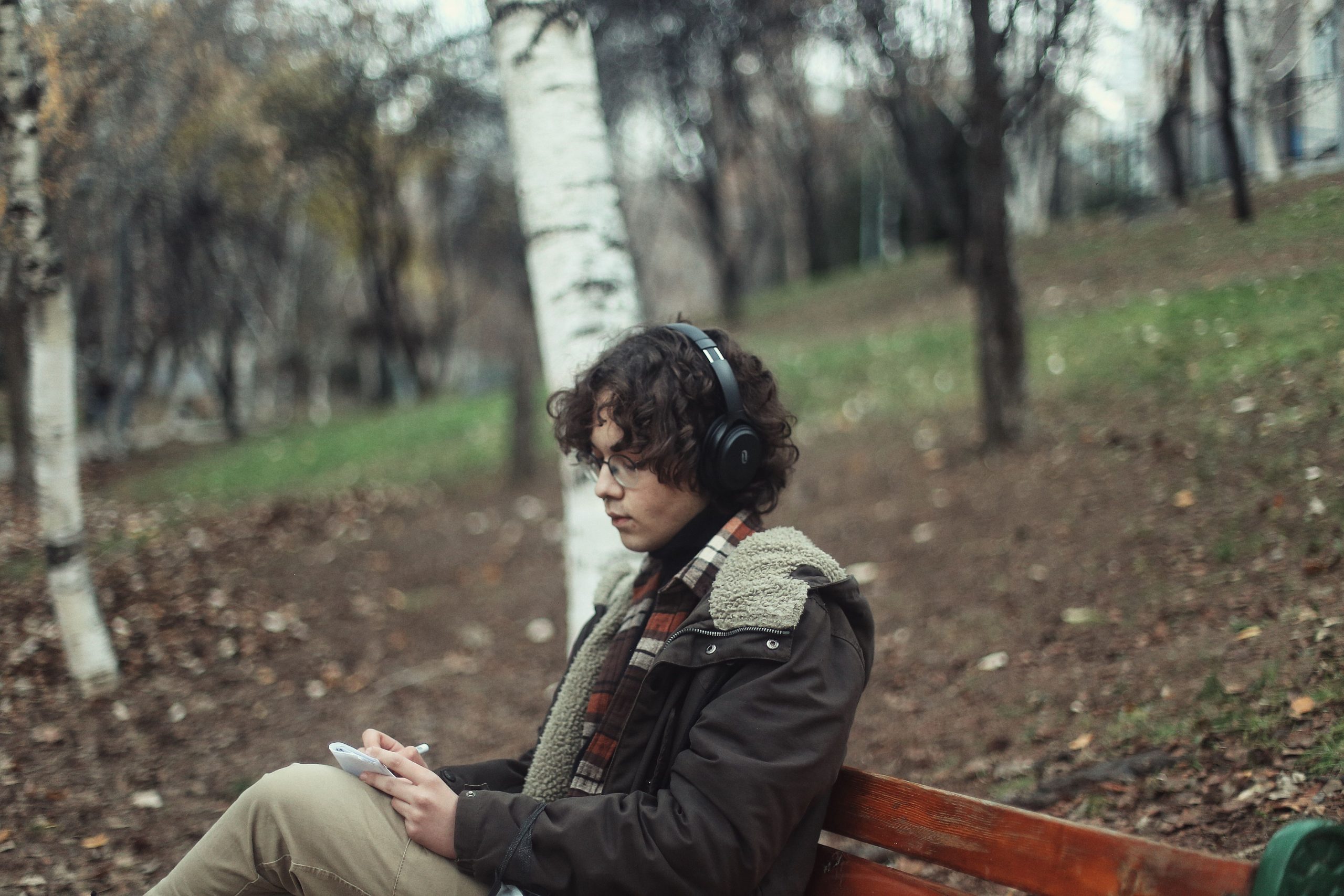 Homme écoutant musique assis banc parc automne
