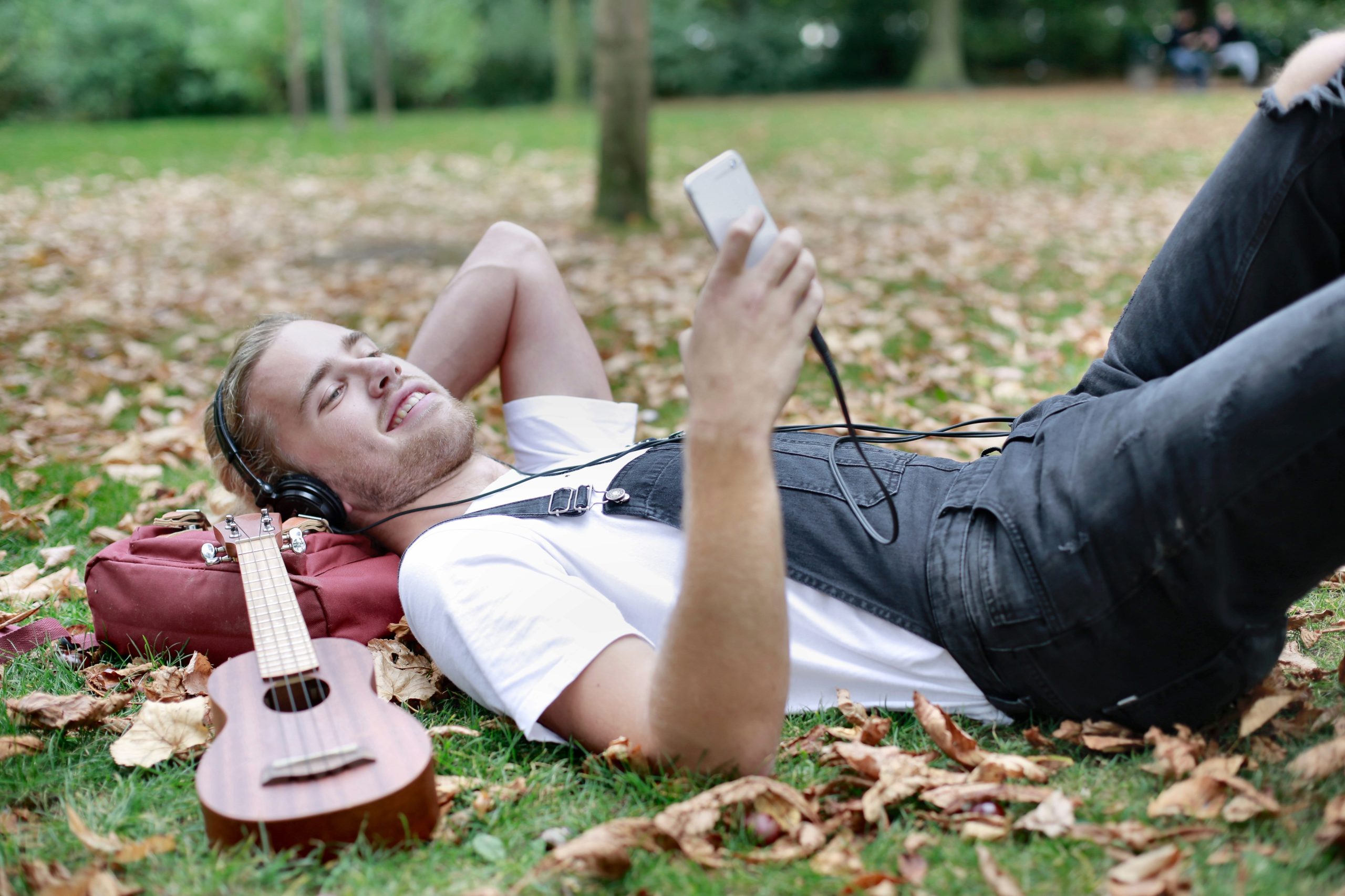 Jeune homme relaxant écoutant musique sur herbe