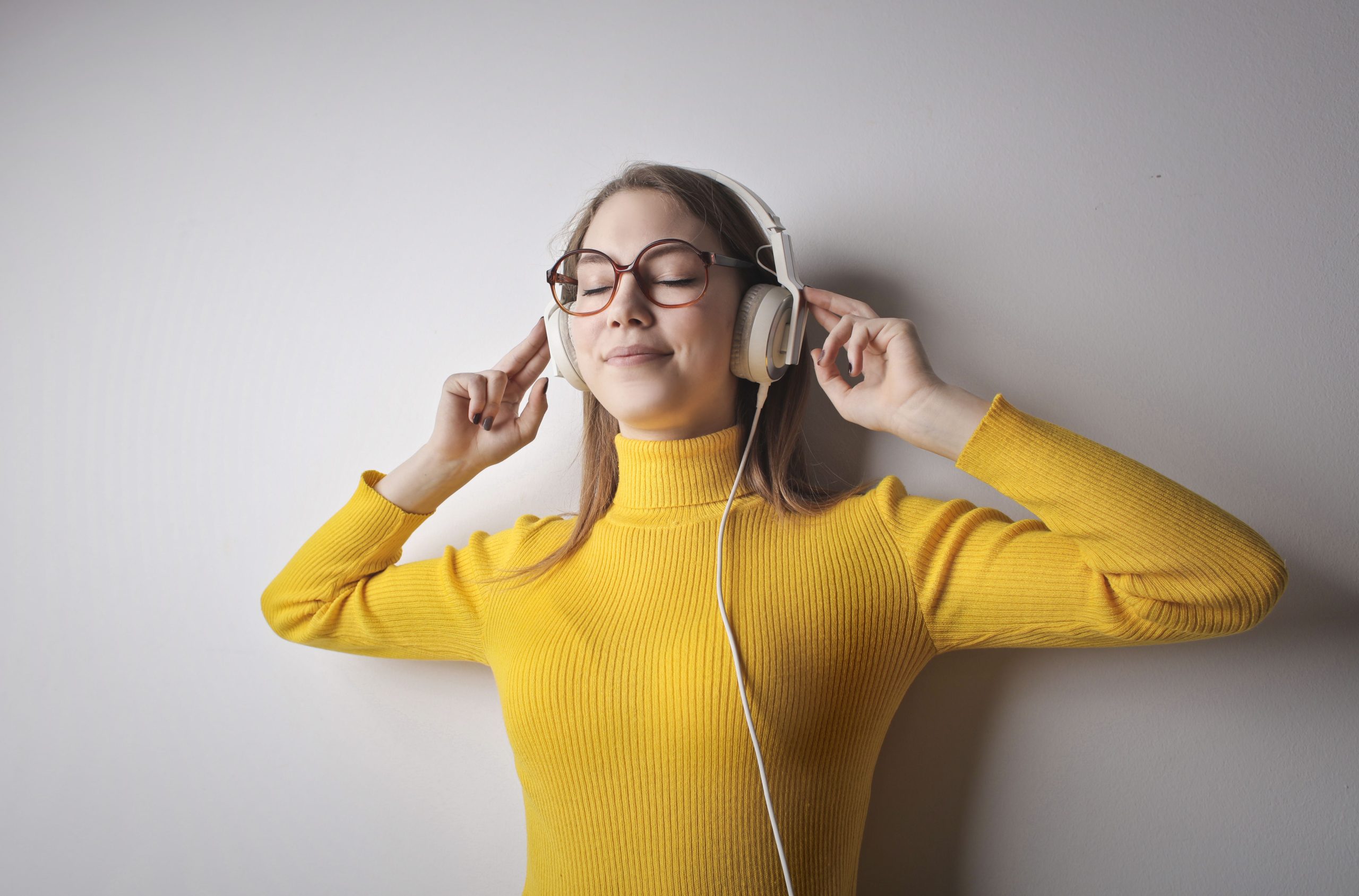 Femme souriante écoutant musique avec casque jaune