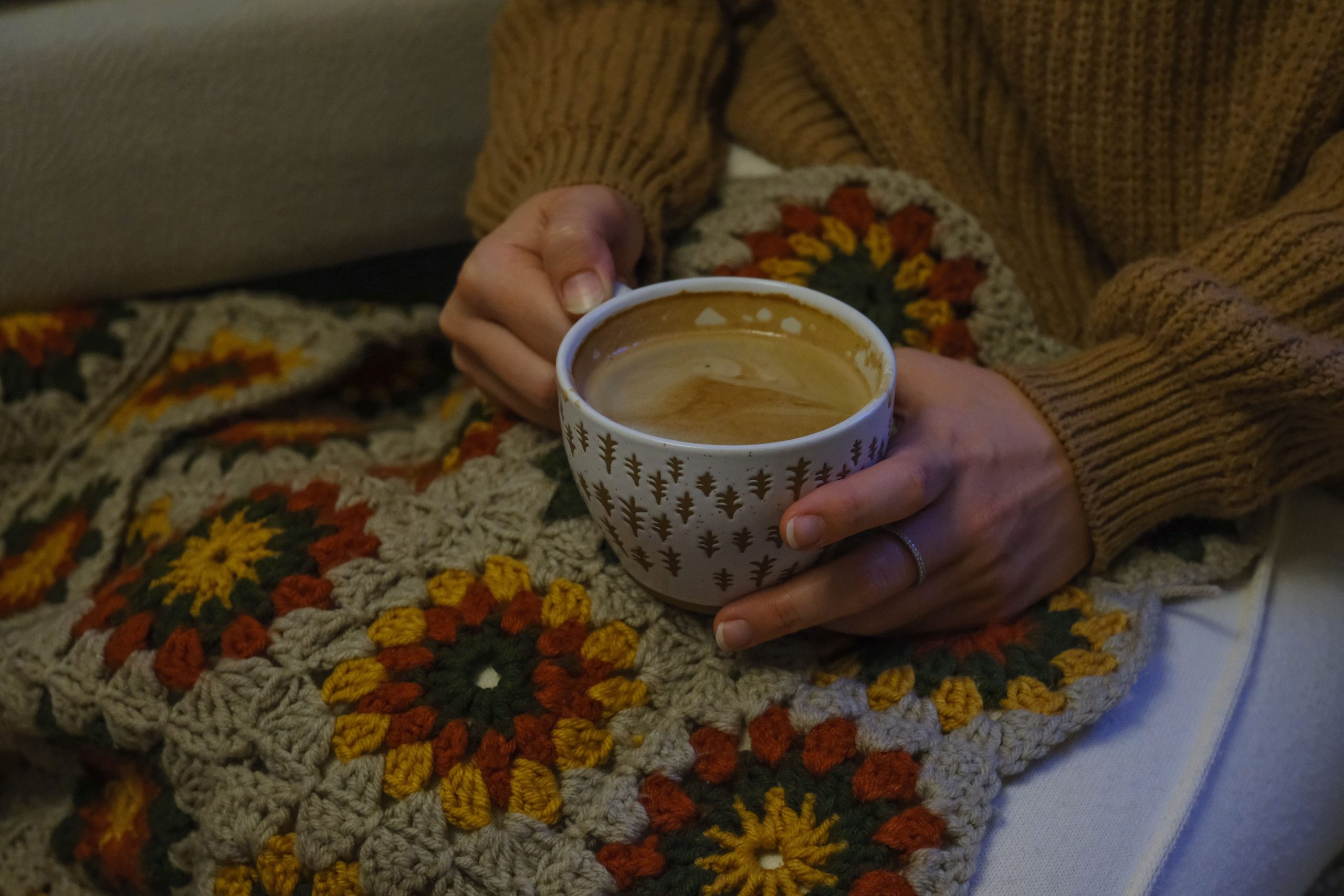 Personne tenant tasse chaude enveloppée couverture crochet confortable