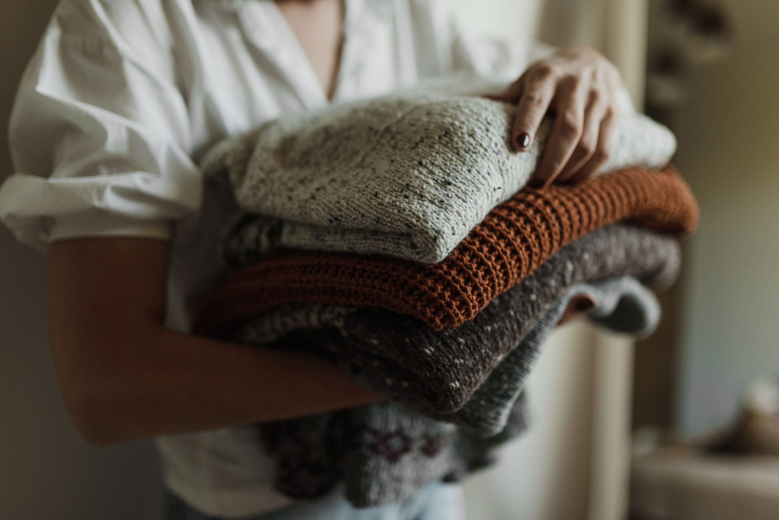 Femme tenant une pile de pulls tricotés chauds.